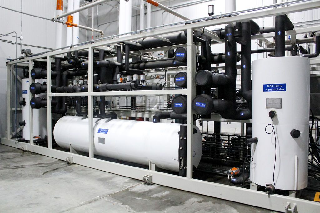 Dense insulated refrigerant piping, filter dryers, and a liquid CO2 receiver on a skid-mounted industrial rack
