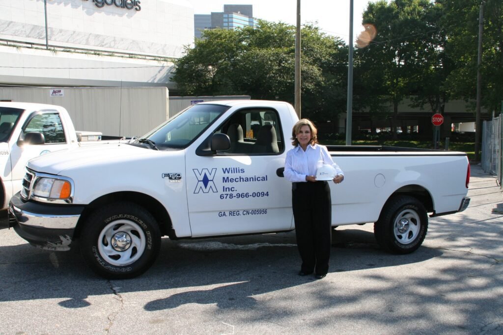 Willis Mechanical team member with branded truck, hard hat in hand