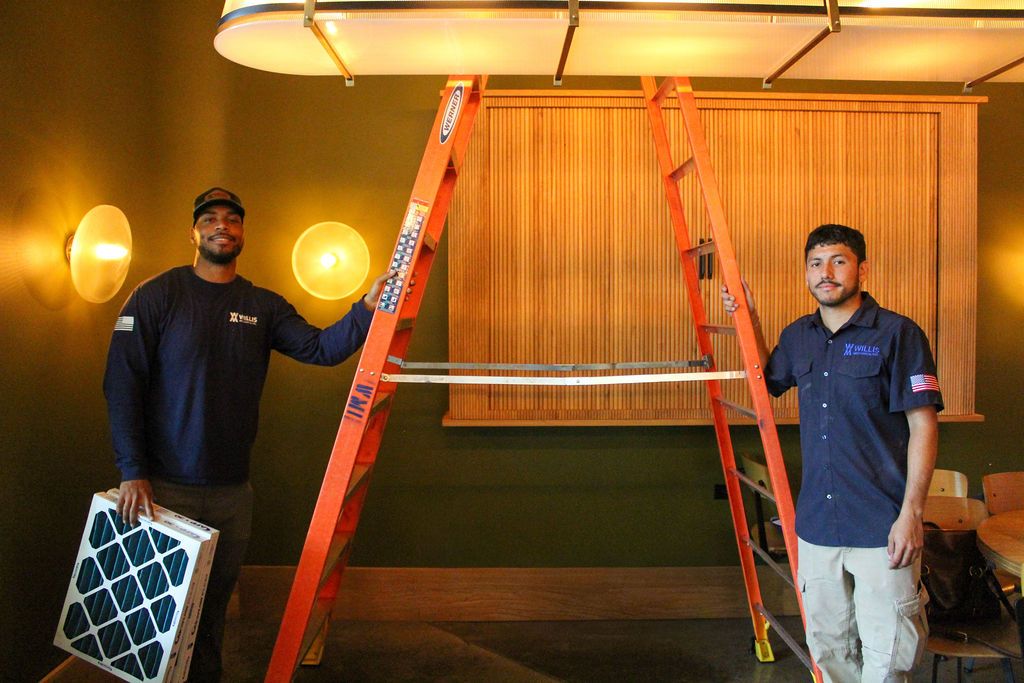Two Willis Mechanical technicians standing beside a stepladder on a job site