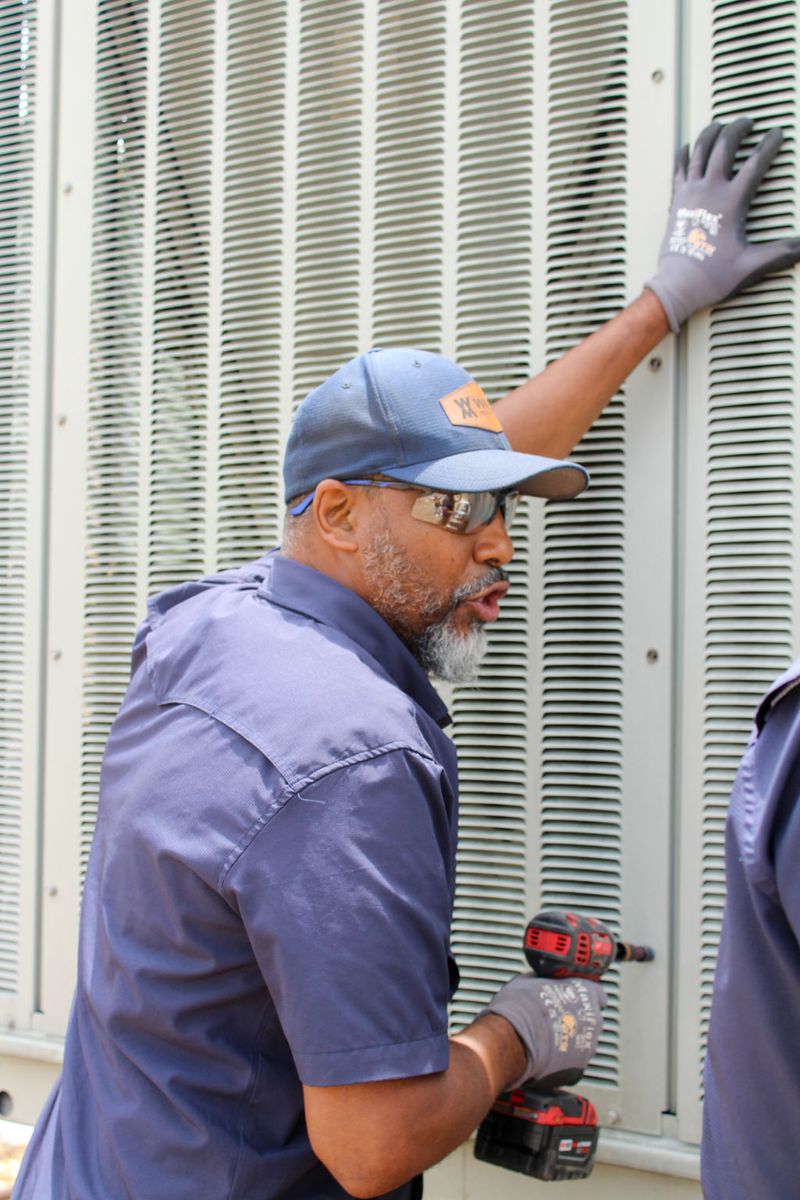 Technician driving a fastener into a louvered rooftop panel